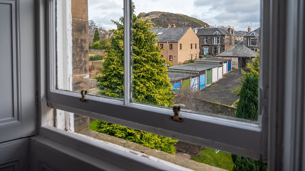 Widok z wnętrza domu, przez częściowo uchylone okno.